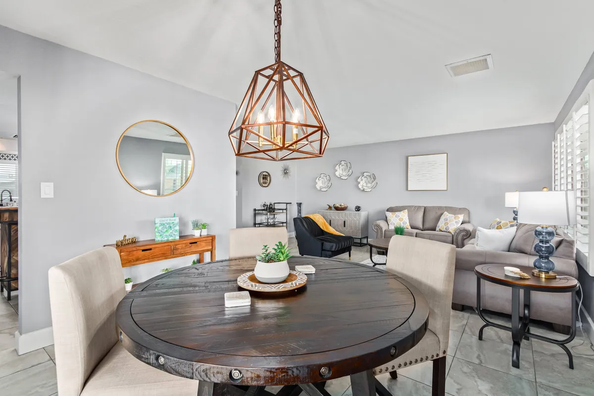 A cozy, well-lit dining space with a round wooden table, geometric pendant lighting, and comfortable seating. The area is designed for relaxed, communal dining, with a warm, inviting atmosphere that encourages conversation and togetherness.