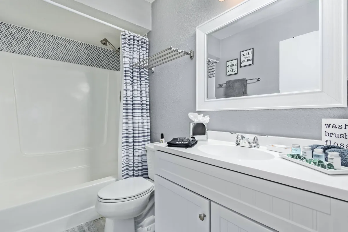 A refreshing, modern bathroom featuring a vanity with a sink, large mirror, and decorative items on the counter. The walk-in shower area is visible, adding both functionality and style. The bright, tidy layout exudes a sense of calm and readiness for daily routines.