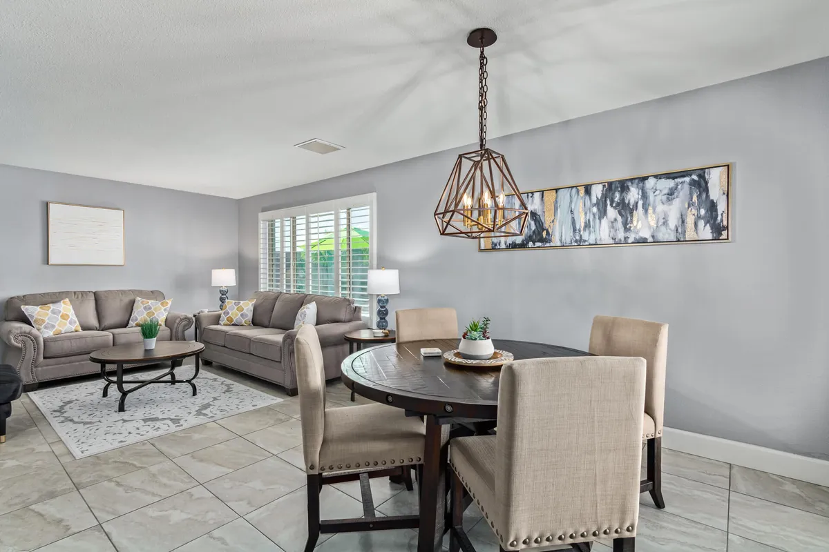 This image displays a seamless open-concept interior where comfortable sofas are positioned near a dining table. A decorative light fixture and artwork on the wall further enhance the warm, connected vibe. The sightlines between living and dining spaces echo the section's narrative of uninterrupted group interaction.