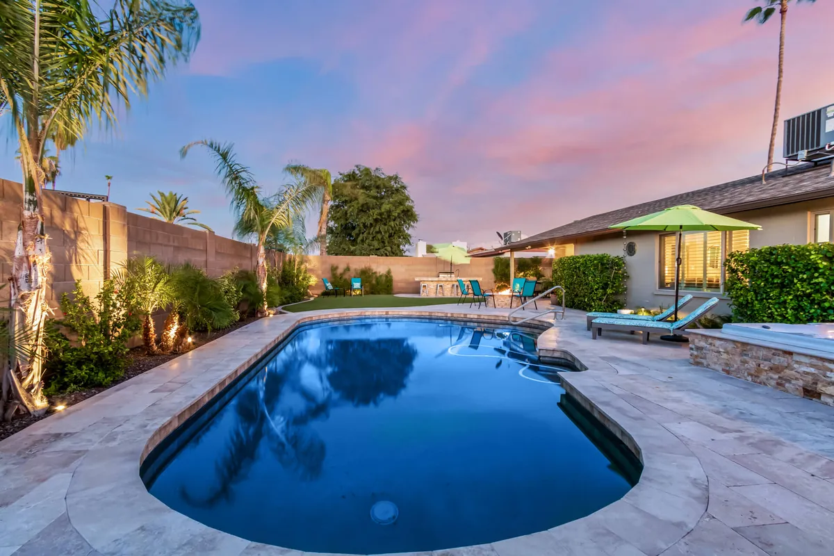A sparkling swimming pool surrounded by lounge chairs, palm trees, and a spacious patio area. The outdoor setup invites relaxation after a day on the fairways, blending luxurious comfort with classic Arizona style.